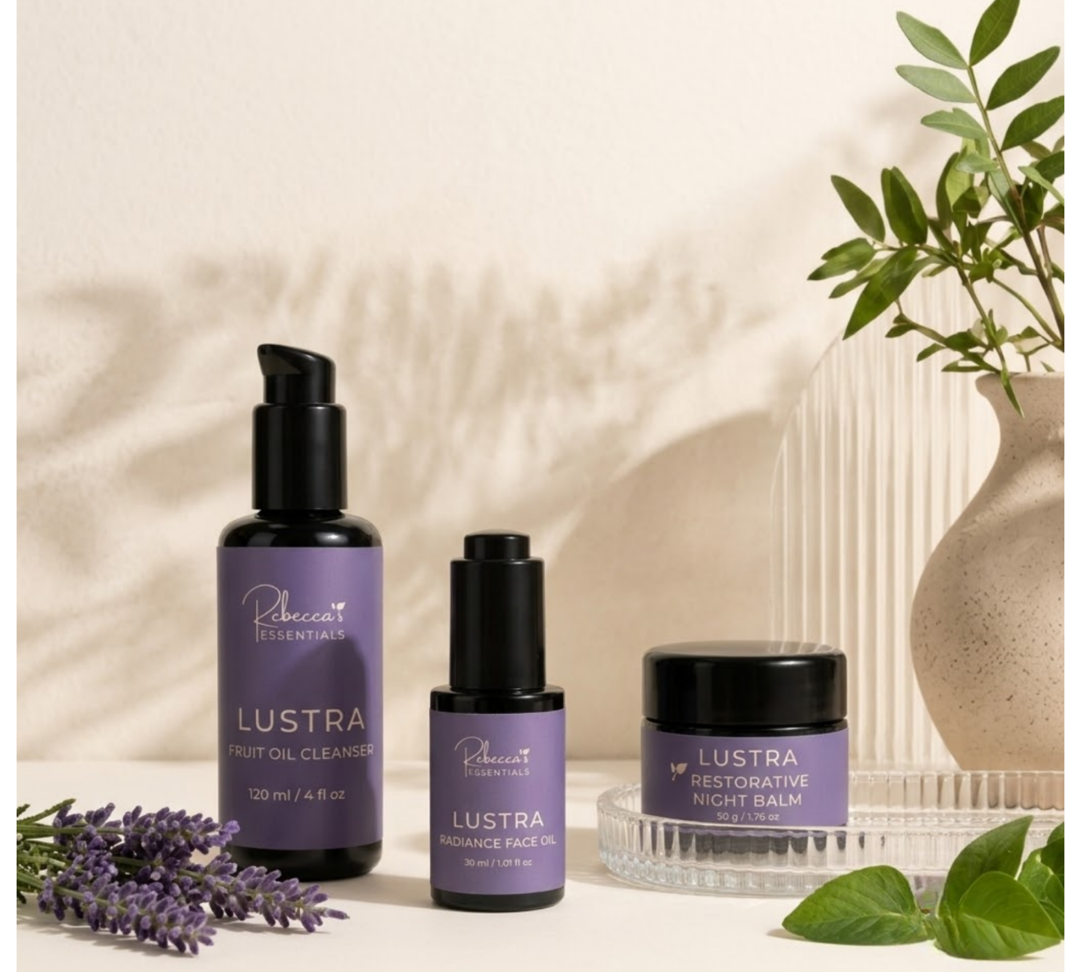 The Essential Trio — cleanser, face oil, and night balm arranged on a light beige surface with soft shadows.