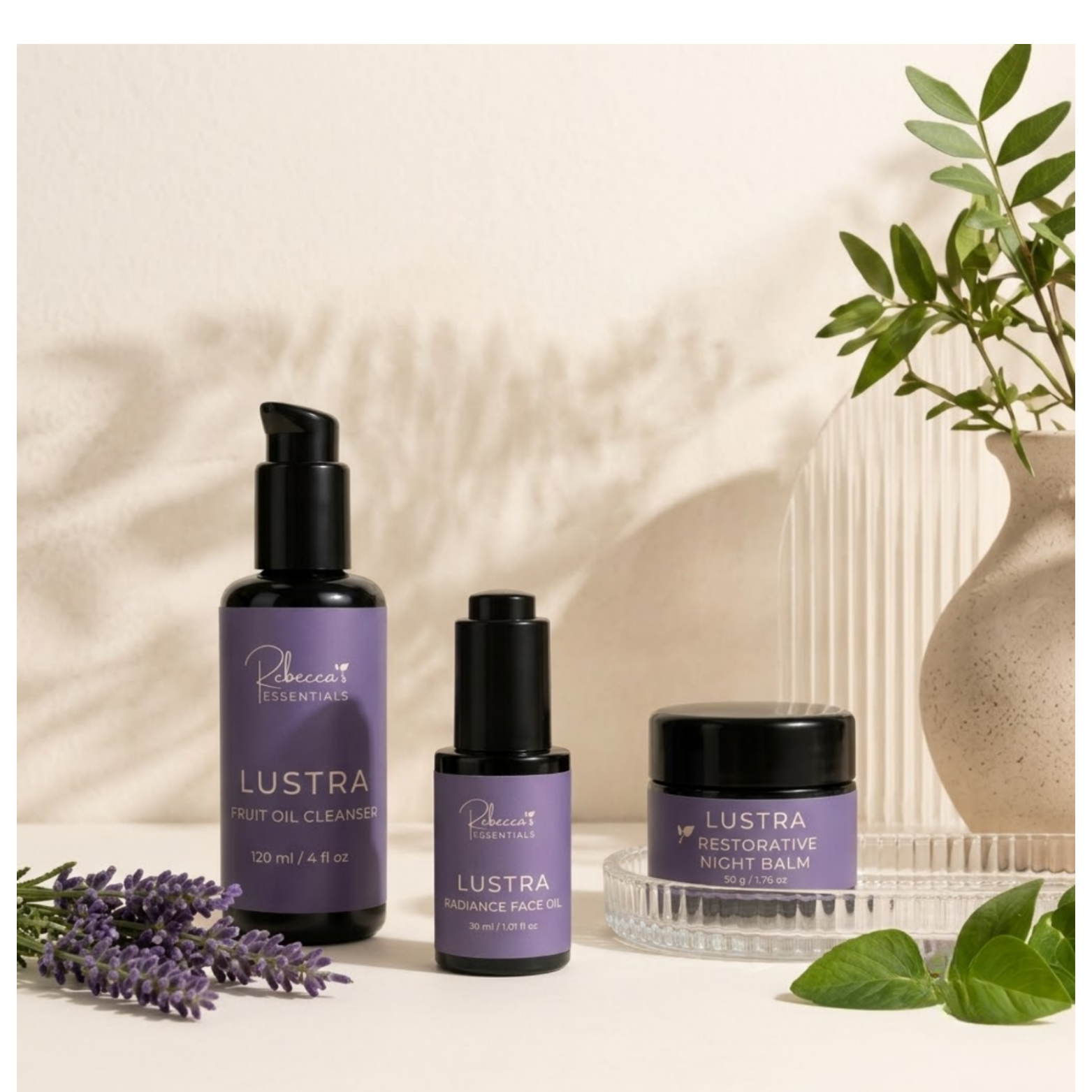 The Essential Trio — cleanser, face oil, and night balm arranged on a light beige surface with soft shadows.